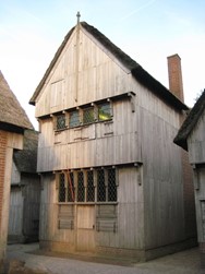 <p>Reconstructie van een 14e eeuws houten huis met een verdieping met daarnaast en tegenover verdiepingloze houten huizen (Archeon). </p>
